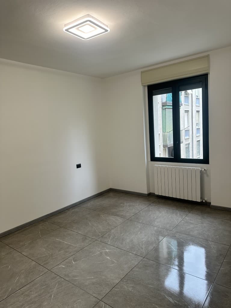 Camera da letto vuota con finestra e pavimentazione chiara